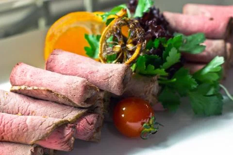 Thinly sliced beef with cherry tomatoes, lettuce and oranges Stock Photos