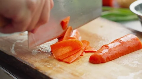 Thinly sliced carrots with Chinese kitchen knife on wooden cutting board Vidéo 341503989