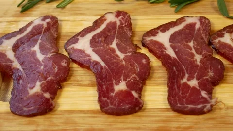 Thinly sliced cured meat pieces on a wooden board Stock Footage 319418788