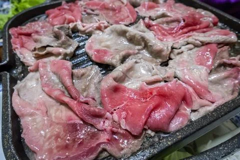 Thinly sliced pieces of beef in the process of being fried on a hot metal pan Stock Photos