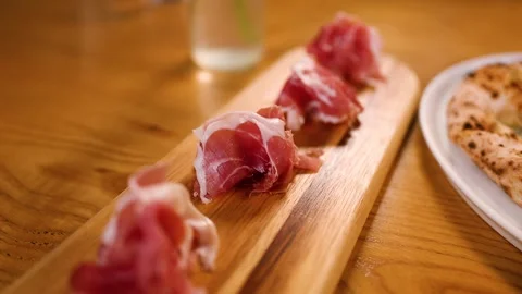 Thinly Sliced Prosciutto Ham Served on a Wooden Board Stock Footage 337877096