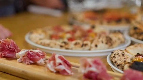 Thinly Sliced Prosciutto Ham on Wooden Board with Pizza Background Stock Footage 338054752