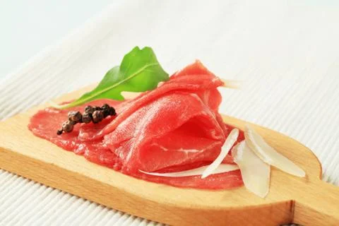 Thinly sliced raw beef meat on cutting board Stock Photos