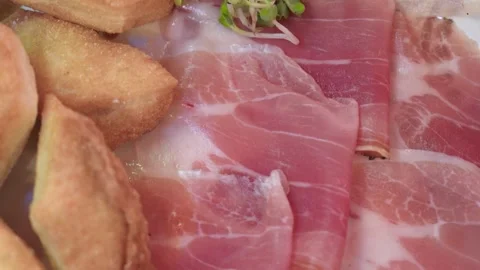 Thinly sliced Tuscan raw ham with pecorino on rustic dish Stock Footage 336691781