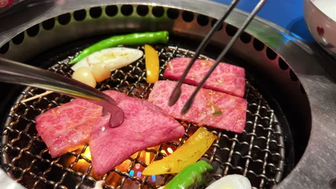 Thinly sliced beef and vegetables on a table-top barbecue grill Stock Footage 237243499