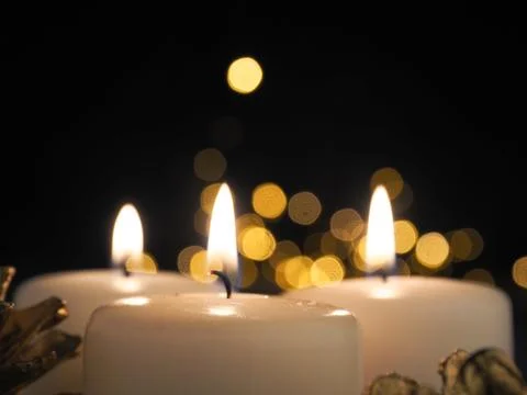 Third Advent candle burning with blurred Christmas lights Stock Photos