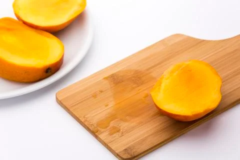 Third of a mango and its juice on wooden board Stock Photos