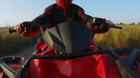 Third-person camera.A girl rides a red ATV through a field.A girl rides off-road Stock Footage 208633383