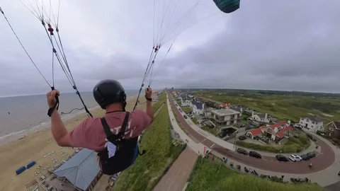 Third person point of view follows paraglider soaring above beachfront 動画素材 280733001
