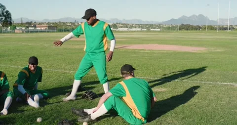 Third player approaching prompts baseball teammates forming semicircle on grass, Stock Footage 335808051