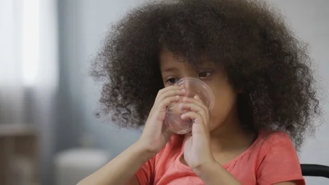 Thirsty Afro-American kid drinking still mineral water, close-up of child's face 스톡 동영상 80649952