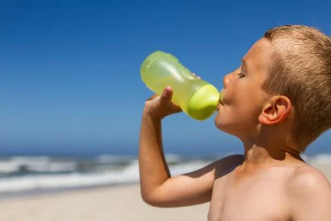 Thirsty boy drinking from water bottle Stock Photos