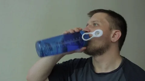 Thirsty man drinking from the blue bottle. Video stock 77413577