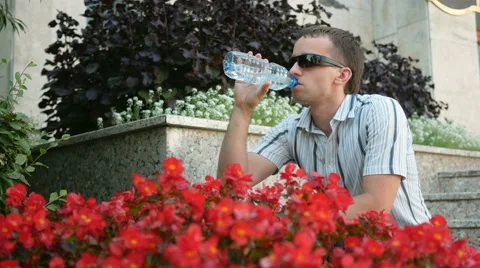 Thirsty man having a break drinking a bottle of water. Man in sunglasses and Stock Footage 66571403