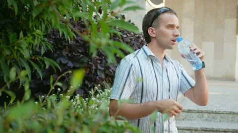 Thirsty man having a break drinking a bottle of water. Man in sunglasses and Stock Footage 66572983