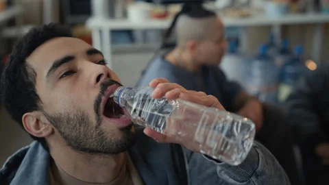 Thirsty Middle Eastern Man Drinking Water from Bottle at Relief Site Vídeo Stock 339067647