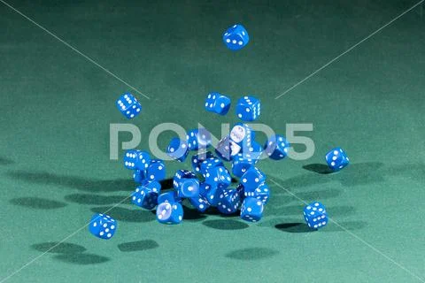 Thirty blue dices falling on a green table Stock Photos