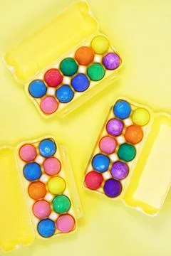 Thirty multicolored easter eggs in yellow egg boxes on yellow background Stock Photos