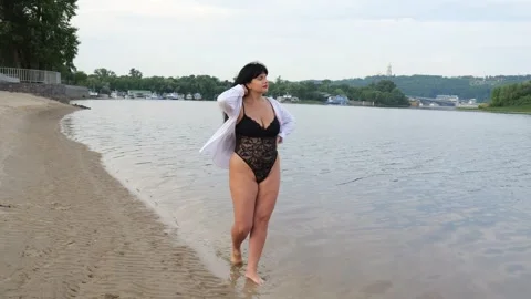 A thirty year old plus size model in black lingerie with a white shirt walks Vidéo 244633177
