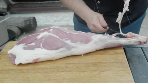 Thorough processing of lamb leg by deboner on open air Stock Footage 247761902