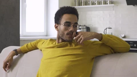 Thoughtful African guy sitting on the couch 库存影片 166196563