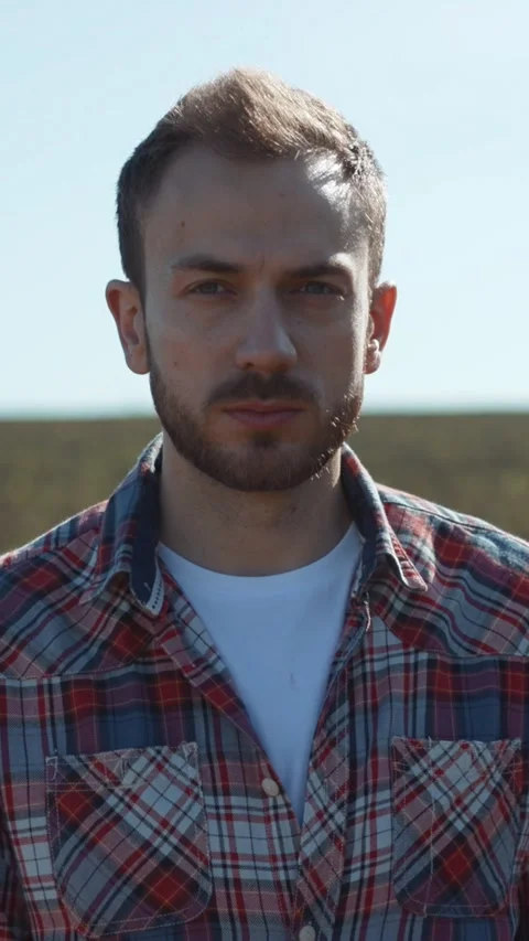 A thoughtful and pensive man dressed in a stylish plaid shirt stands in a serene Stock Footage 306613641