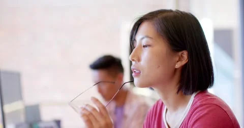 Thoughtful asian female creative working at computer in casual office, slow Stock Footage 336896790