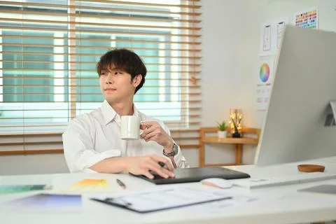 Thoughtful asian man web developer drinking coffee and looking through window Stock Photos