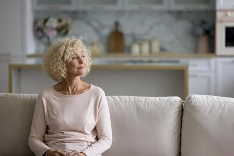 Thoughtful attractive blond middle-aged woman staring into distance Stock Photos