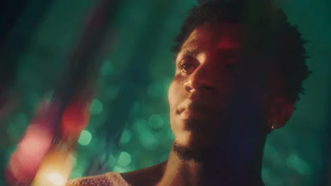 Thoughtful Black Man Looking through ShimmeringTinsel Curtain Stock Footage 316542525