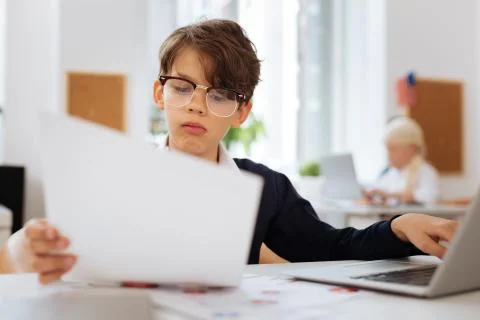 Thoughtful boy checking a document on a laptop Stock Photos