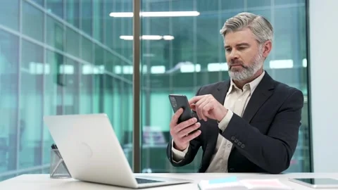 Thoughtful businessman is using browsing mobile sitting at desk phone Stock Footage 312732685
