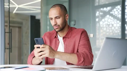 Thoughtful businessman is using browsing mobile phone while sitting at workplace Video stock 340880666