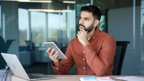 Thoughtful businessman is using digital tablet sitting at workplace in business  Stock Footage 305655364