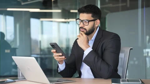 Thoughtful businessman is using mobile phone sitting at workplace in business  Stock Footage 318218663
