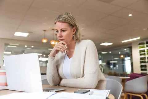 Thoughtful caucasian female business creative using laptop at workplace Stock Photos
