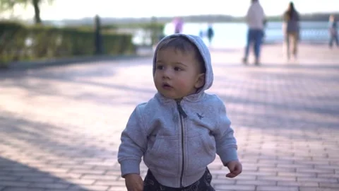 Thoughtful child. A one-year-old boy in a hood walks in the park. Slow motion. Stock Footage 243354587