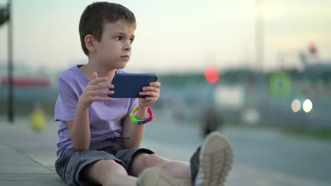 A thoughtful child sits on the steps on the sidewalk and looks around and into Stock Footage 204101354