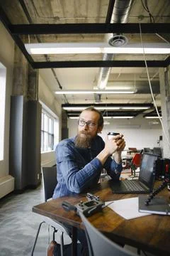 Thoughtful computer programmer drinking coffee at laptop in office Stock-Fotos