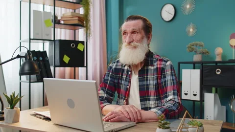 Thoughtful concerned senior man working on laptop computer looking away thinking Stock Footage 312453944