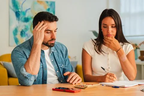 Thoughtful couple at table solving documents and notes during a focused Stock Photos