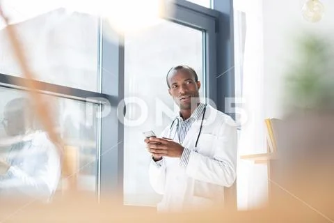 Thoughtful dark-skinned medical worker looking aside Stock Photos