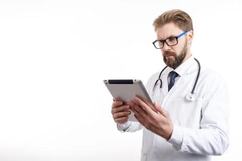 Thoughtful Doctor With Beard Checking Information via Tablet Foto stock