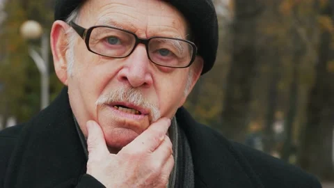 Thoughtful elderly senior rubbing his chin and looking aside with pensive Stock Footage 143730171