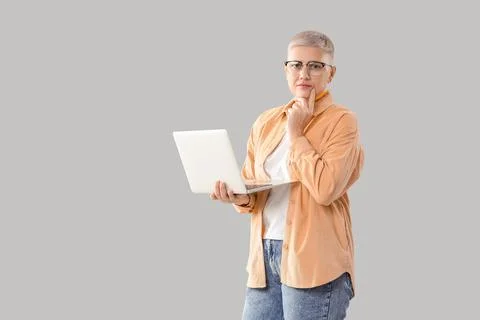 Thoughtful female programmer with laptop on light background Stock Photos