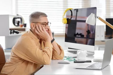 Thoughtful female programmer sitting at desk in office Stock Photos