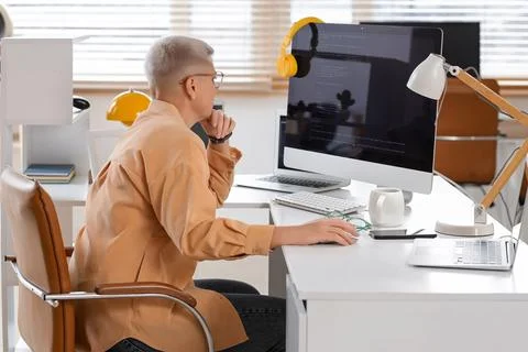 Thoughtful female programmer working at desk in office Stock-Fotos