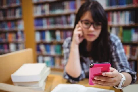 Thoughtful female student using a mobile phone 스톡 사진