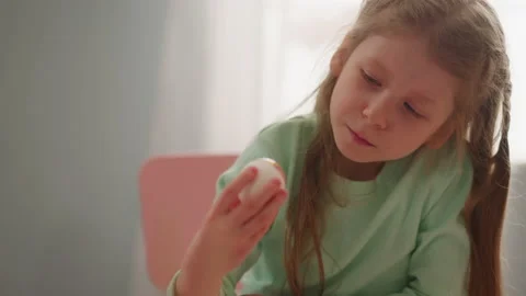 Thoughtful girl holds Easter egg colored with marbling Stock Footage 172365299