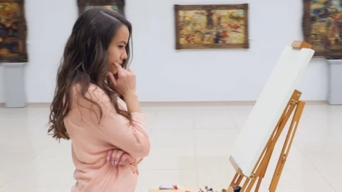 Thoughtful girl standing in front of blank canvas. Stock Footage